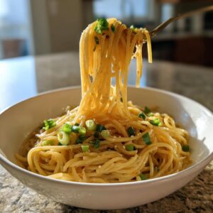 A bowl of delicious 15-minute garlic noodles, garnished with fresh scallions and served on a countertop.