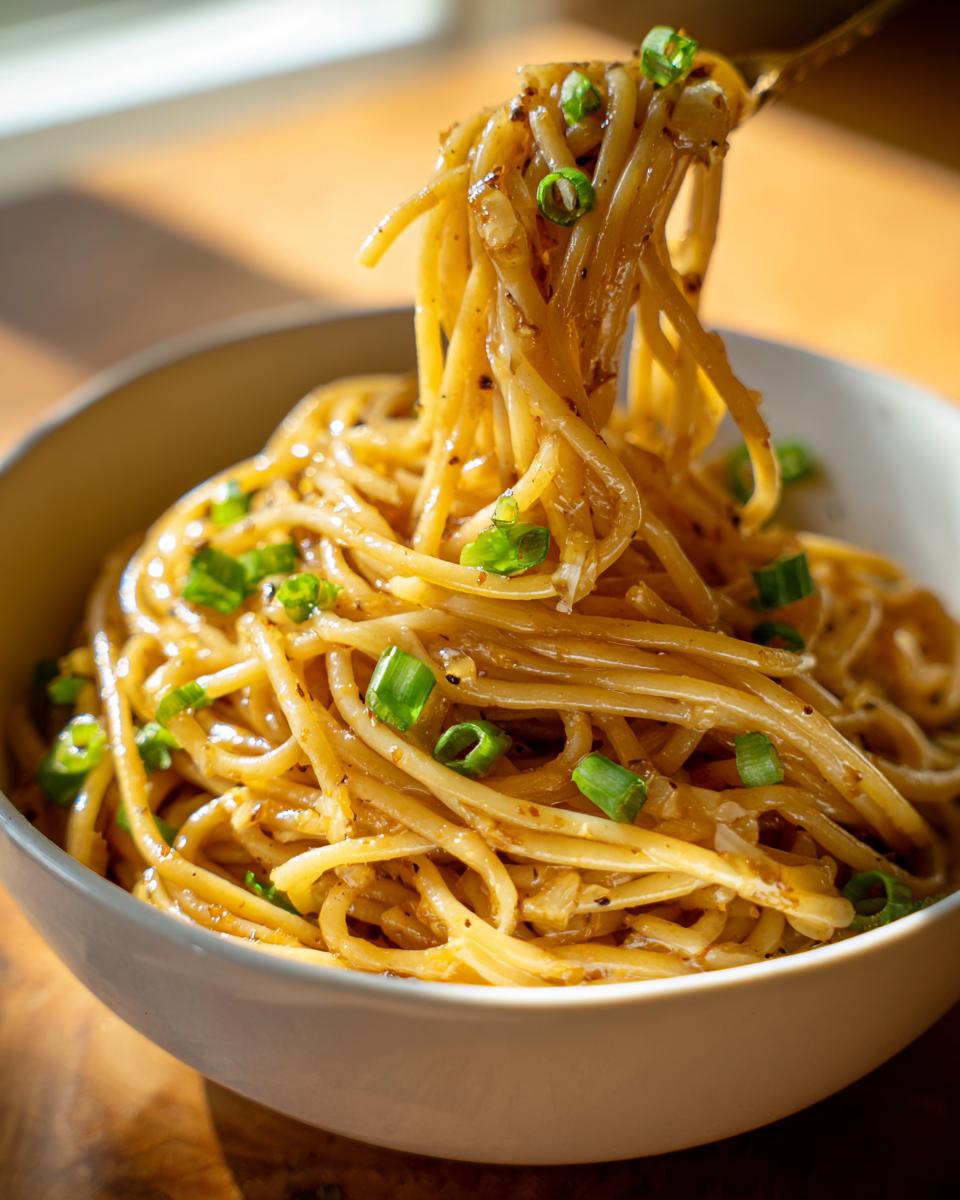 Close-up of a bowl of delicious 15-minute garlic noodles, garnished with fresh green onions.