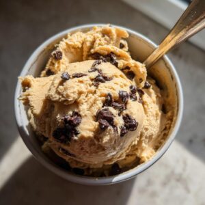 Overhead shot of a bowl filled with high protein cookie dough and chocolate chips, with a spoon.