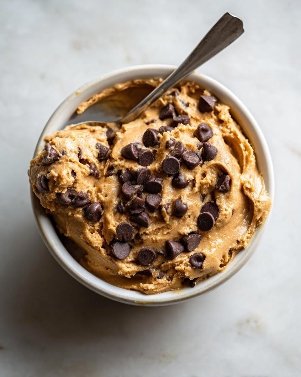 Overhead shot of a bowl of high protein cookie dough with chocolate chips and a spoon.