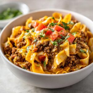 A close-up of a bowl of One pot taco pasta, topped with tomatoes, cilantro, and melted cheese.