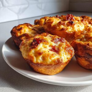 A plate of freshly baked pizza muffins, showcasing their golden-brown tops and cheesy, savory fillings.