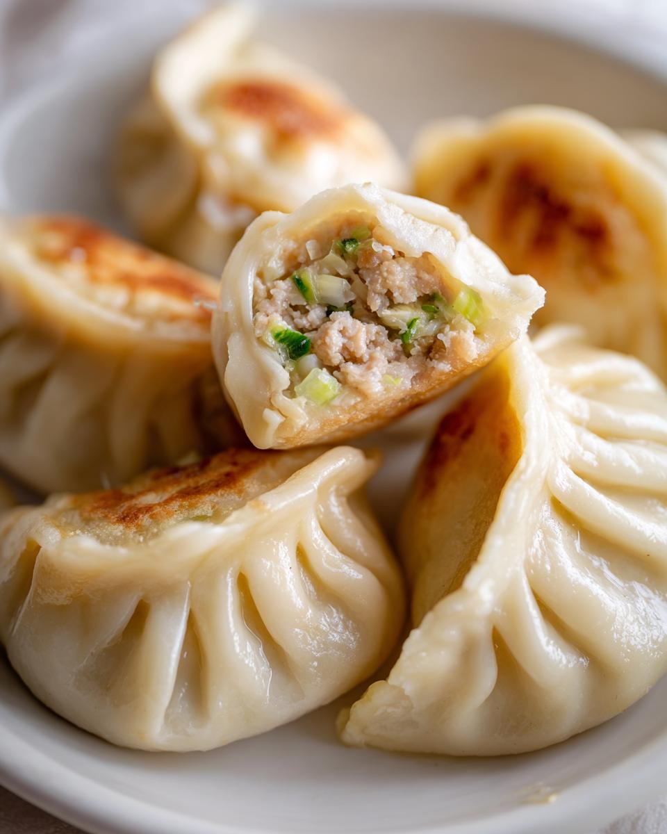 Close-up of Traditional Chinese Dumplings, one cut open to show the savory filling of meat and vegetables.