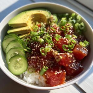A vibrant Tuna Poke Bowl with tuna, avocado, cucumber, rice, and sesame seeds.