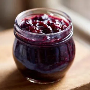 Close-up of a jar filled with rich, dark homemade blueberry jam, showcasing its texture and color.