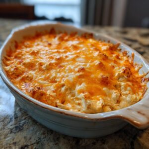 Baked buffalo chicken dip in a white baking dish, topped with melted cheese. Ready to serve.