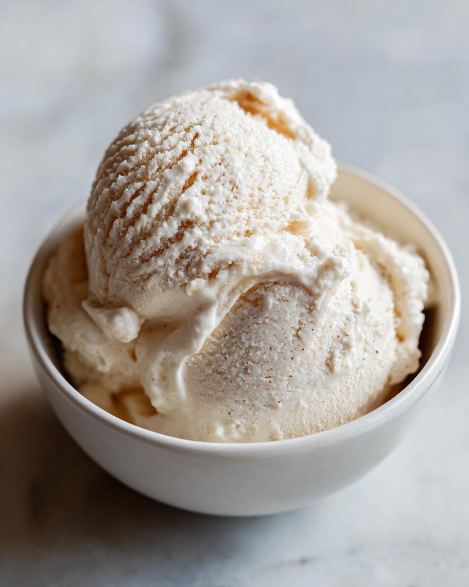 Two scoops of homemade cottage cheese ice cream in a white bowl, ready to eat.