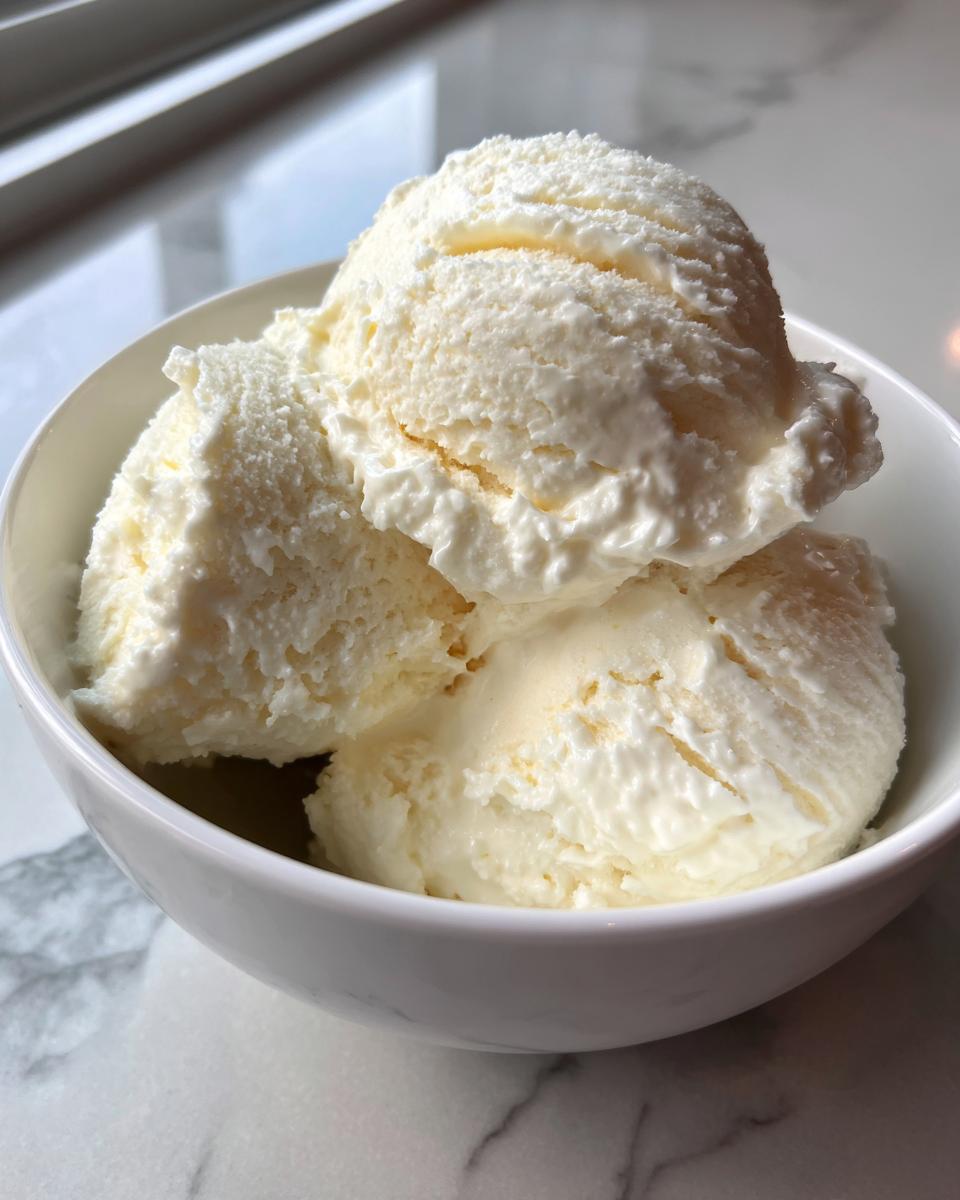 Three scoops of creamy cottage cheese ice cream in a white bowl, ready to eat.