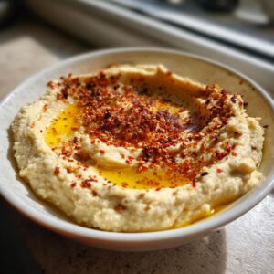 A bowl of creamy Homemade Hummus drizzled with olive oil and sprinkled with spices.