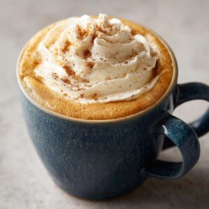 A delicious Homemade Pumpkin Spice Latte topped with whipped cream and a sprinkle of spice in a blue mug.