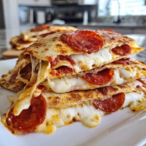 A stack of cheesy pizza quesadillas with pepperoni, showcasing melted cheese and golden-brown tortillas.
