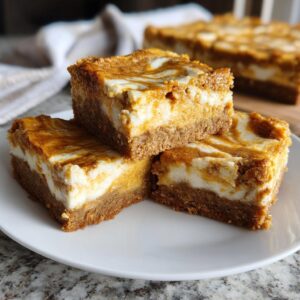 Three pumpkin cheesecake bars stacked on a white plate, showcasing the crust, cheesecake, and pumpkin swirl layers.