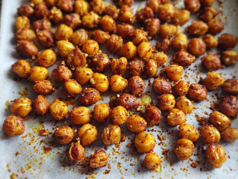 Close-up of crispy Roasted Chickpeas seasoned and spread on a baking sheet.