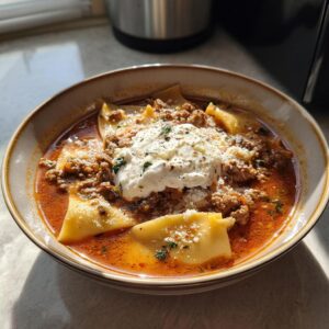 A delicious bowl of crockpot lasagna soup, topped with ricotta cheese, parmesan, and fresh herbs.