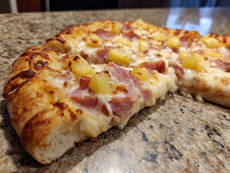 A close-up view of a delicious Hawaiian pizza slice, featuring melted cheese, ham, and pineapple chunks.