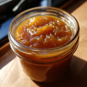 Close up of a jar filled with delicious homemade Pear Butter, glistening in the sunlight.