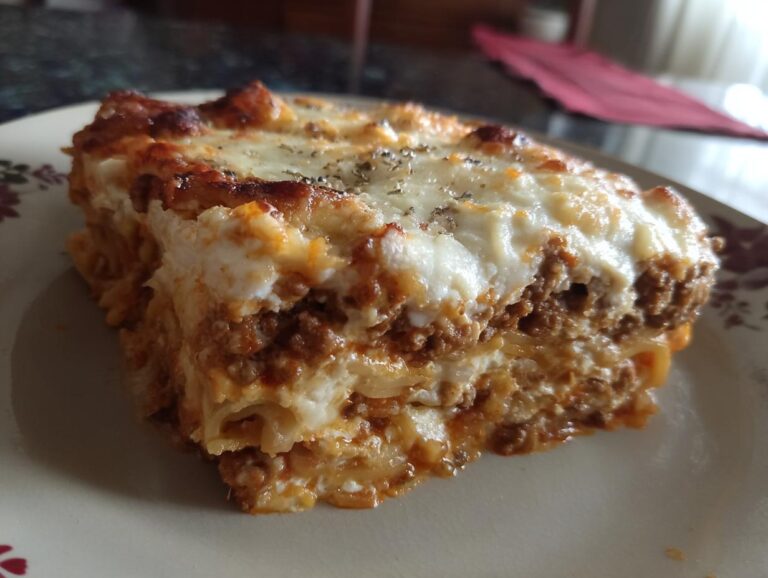 A generous slice of Million dollar spaghetti casserole, showcasing layers of spaghetti, meat sauce, and creamy cheese.