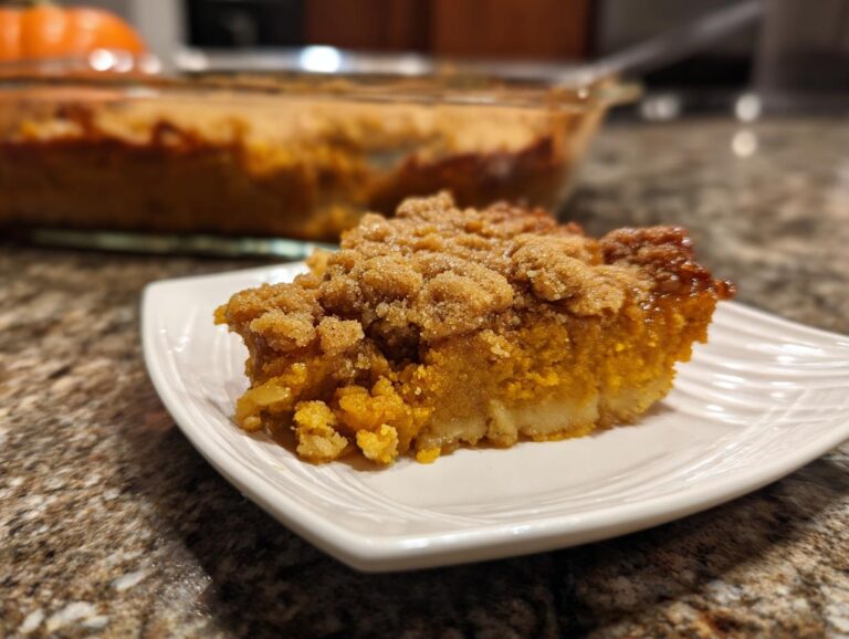 A slice of pumpkin dump cake with a crumb topping on a white plate. Perfect for fall baking.