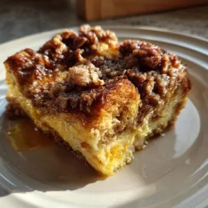 A slice of Pumpkin French toast casserole on a plate, featuring a golden crust and creamy pumpkin filling.