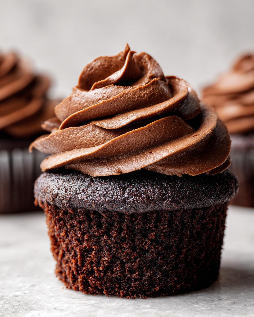 Close-up of a decadent chocolate cupcake topped with swirled chocolate frosting. Amazing Chocolate Cupcakes Recipe.