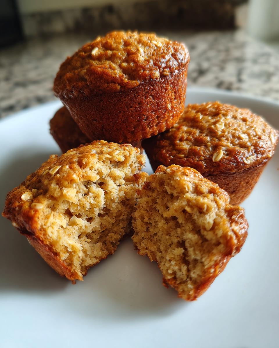 Close-up of a delicious oatmeal muffin split in half, revealing a fluffy interior and visible oats.