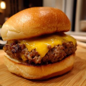 A close-up of a juicy cheeseburger with a perfectly melted cheddar cheese slice on a toasted bun.