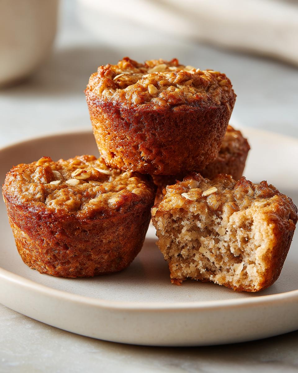 Close-up of delicious oatmeal muffins on a plate, with one muffin showing a bite taken out.