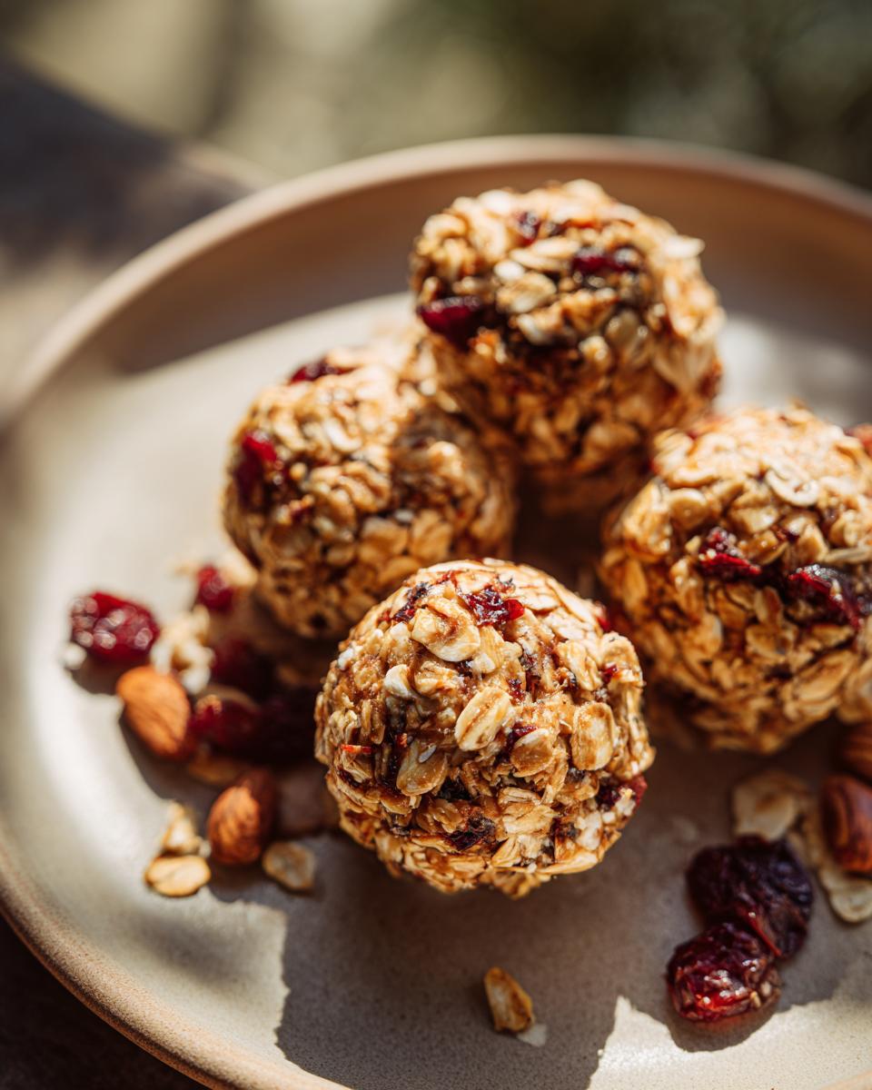 Close-up of peanut butter oatmeal energy bites with dried cranberries and almonds on a plate.