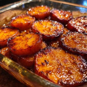 Close-up of sweet, glistening candied yams baked in a glass dish, ready to serve.