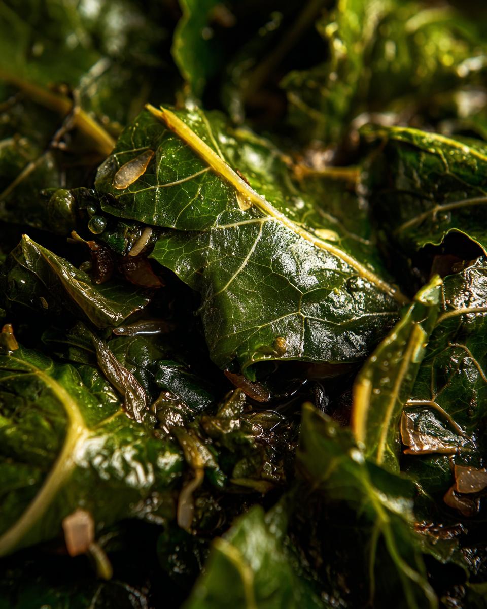 Close-up of tender, braised collard greens with visible stems and chopped onions.