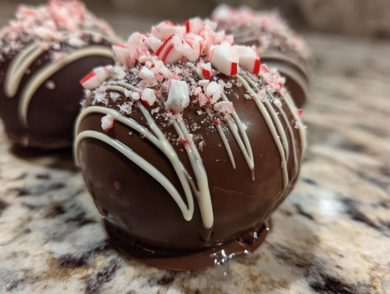 Close-up of a festive hot chocolate bomb, drizzled with white chocolate and topped with crushed peppermint candies.