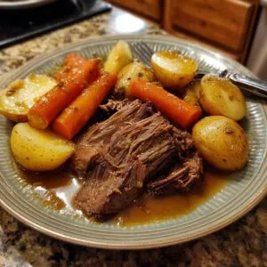 A plate of delicious pot roast served with tender carrots and golden potatoes in savory gravy.