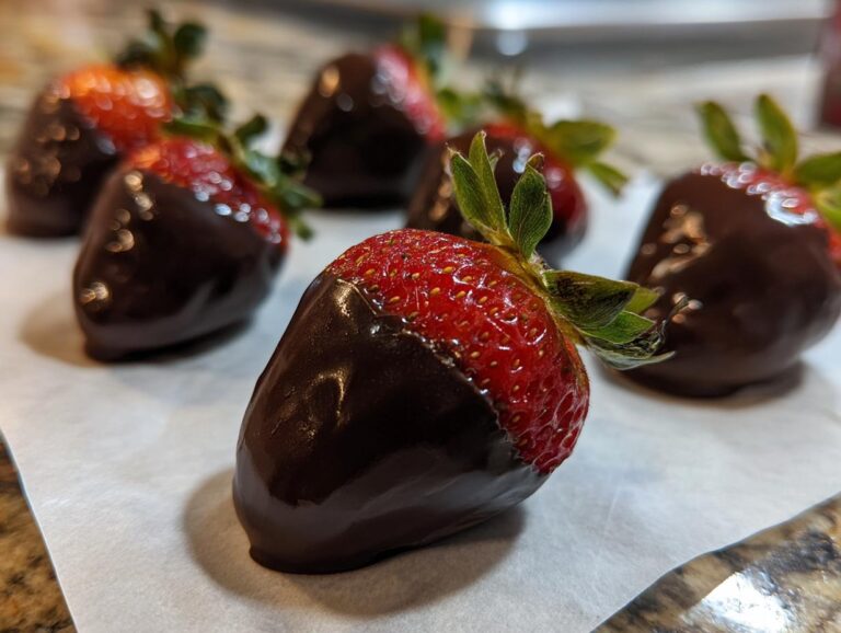 Close-up of fresh chocolate covered strawberries resting on parchment paper to set.